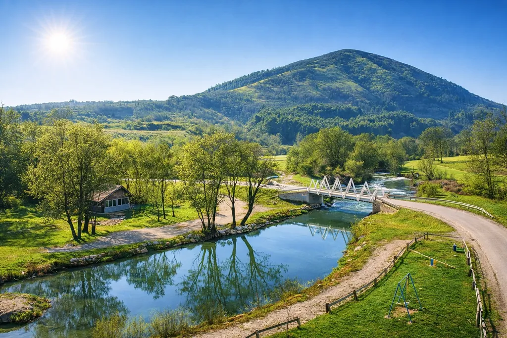 Rijeka Spreča u Kalesiji, mirna voda s odrazom drveća i bijeli pješački most u pozadini, ljetno jutro