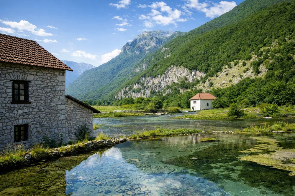 Ali-pašini izvori u Gusinju ljeti ujutro, bistra voda i mali kameni objekti uz planine